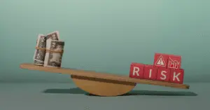 A seesaw with rolled-up dollar bills on one side and red blocks spelling “RISK” on the other, symbolizing financial balance.